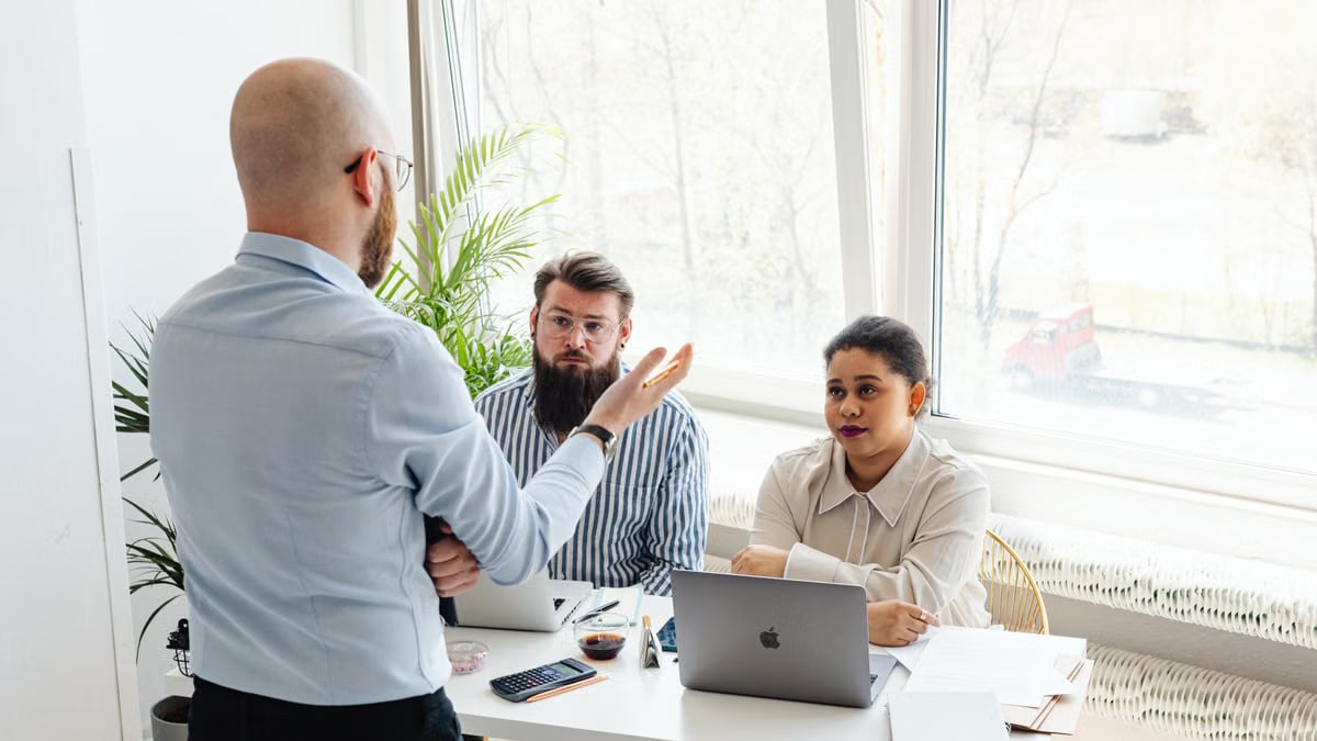 Diverse group of colleagues engaged in a teamwork discussion around a desk in a modern office.